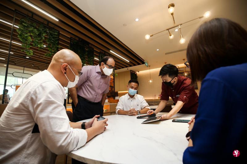 oddle业务总监吴奕杰(右二)向通讯及新闻部长易华仁(站立者)介绍