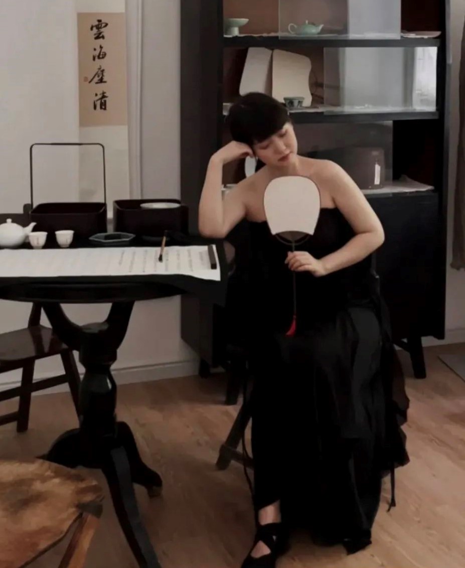 一名佛媛手持团扇,身着抹胸装,在写着经文的书桌上佯装伏案沉思。(互联网)