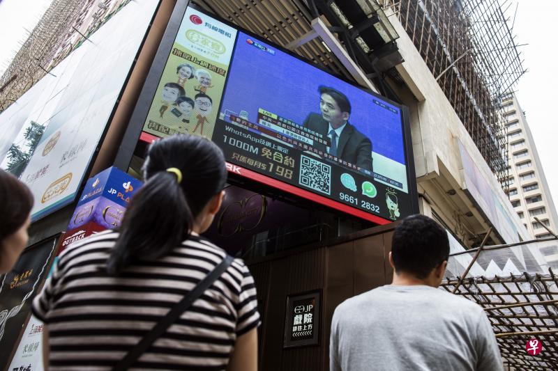 吸引一些香港人在街头看电视直播,电视荧幕中的是发言人杨光