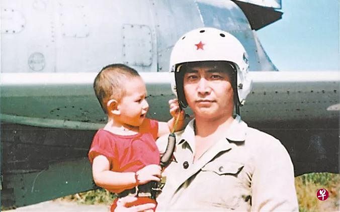 王伟旧照,图为其抱着年幼的儿子在战机前合影.(微信公众号"南海舰队")