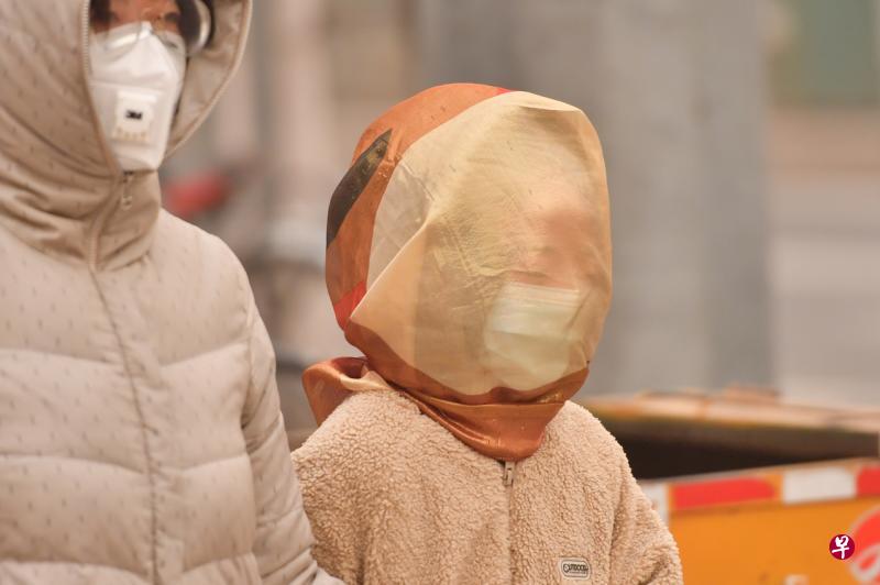 北京市民在沙尘天气中戴着纱巾出行(香港中通社)